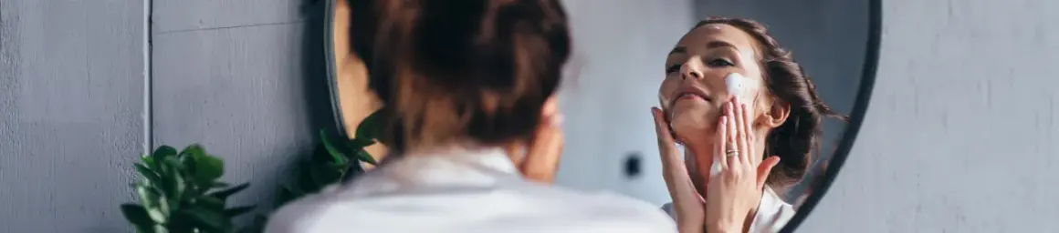 Frau trägt Schaum auf ihr Gesicht auf. Sie fragt sich: "Allantoin, was ist das?" Es ist ein beruhigender Inhaltsstoff für die Haut.