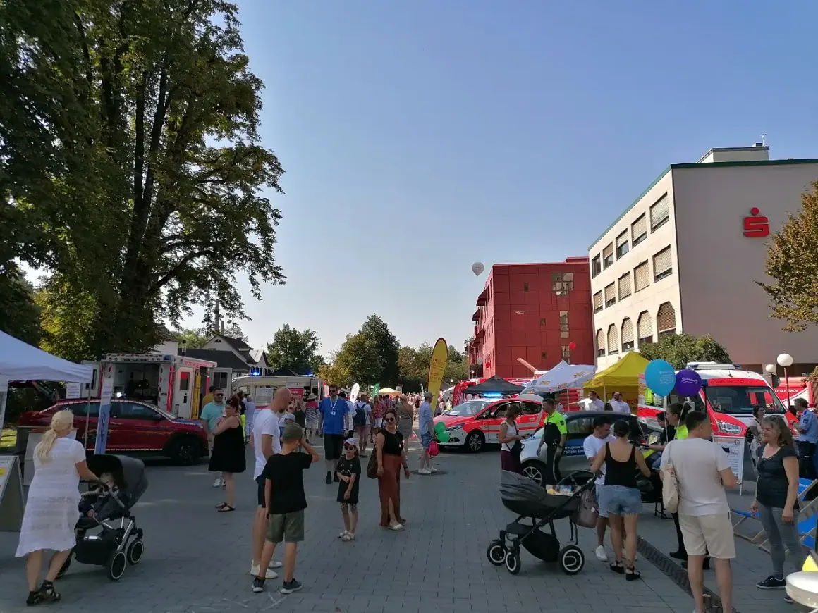 Menschen genießen das Stadtfest Bergisch Gladbach bei Sonnenschein. Einsatzfahrzeuge und Stände säumen die belebte Straße.