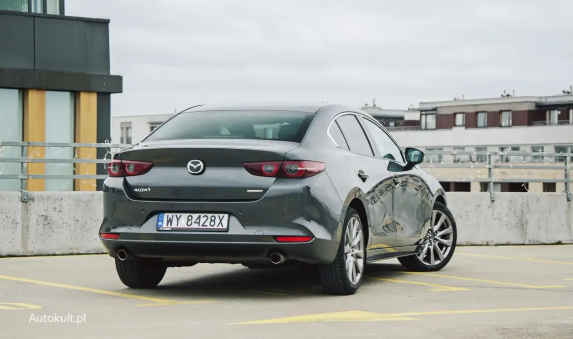 Szary sedan Mazda 3 na parkingu. Sprawdzamy mazda 3 spalanie i wrażenia z jazdy.