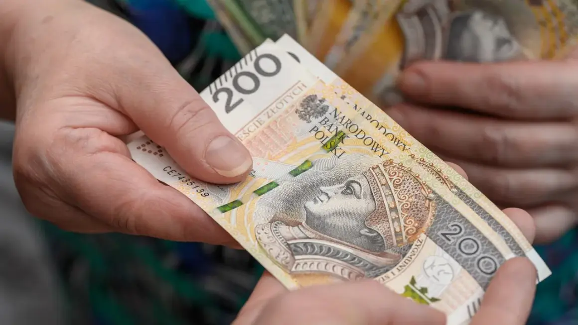 Dwie dłonie przekazują sobie banknot 200 zł. Czy wychowanie dzieci liczy się do emerytury?