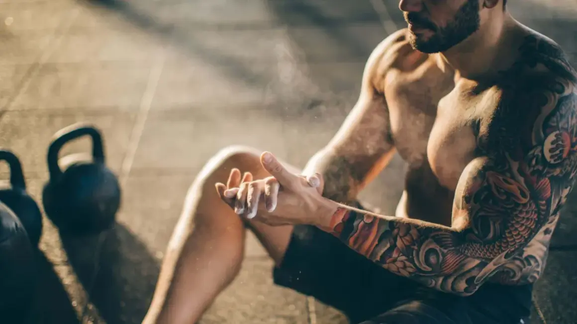 Mann mit beeindruckendem Tattoo auf Brust und Arm, der sich für das Training vorbereitet.