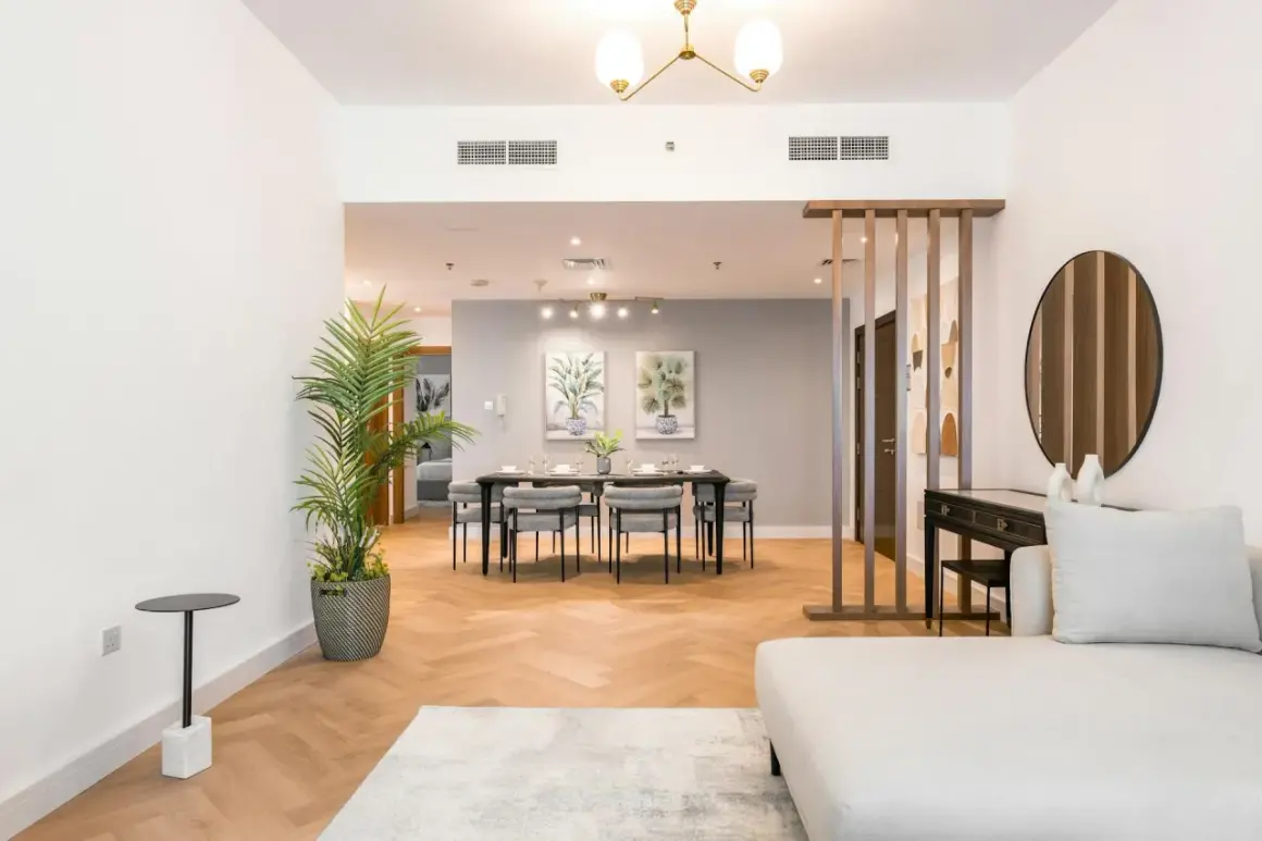 A modern living and dining area, showcasing excellent real estate photography lighting. The space features a sofa, dining table, and decorative elements.