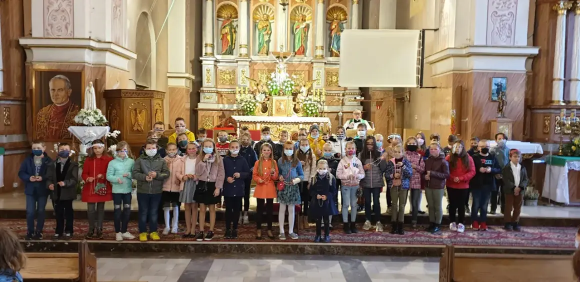 Dzieci w kościele, każde z różańcem w ręku, zastanawiają się, czy można samemu poświęcić różaniec.