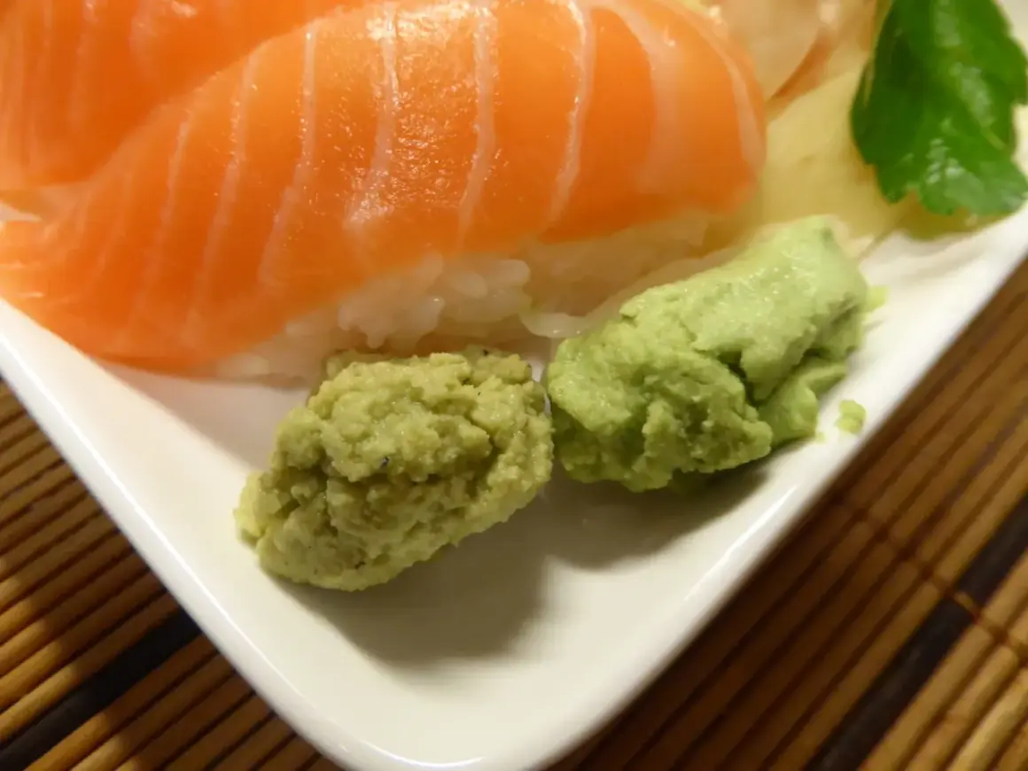 Närbild på sushi med lax och ris, serverad med två klickar grön wasabi. Perfekt för ditt wasabi recept!