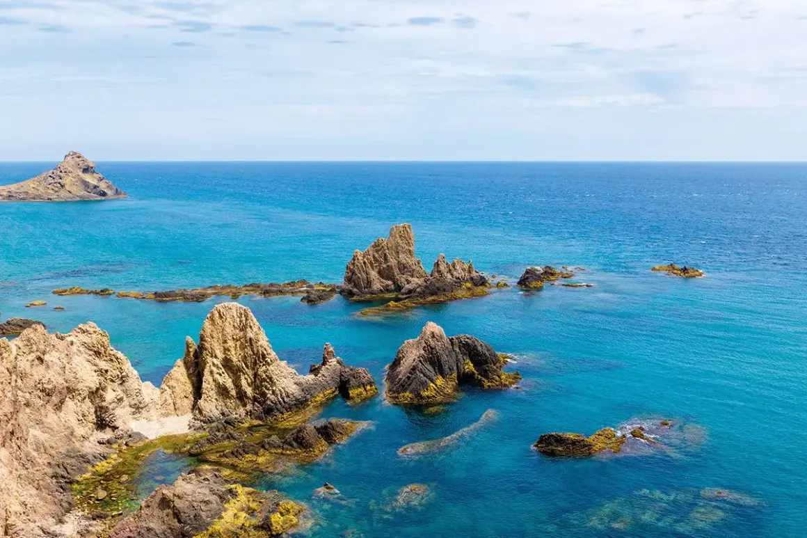 Formaciones rocosas emergen del mar turquesa, como un arrecife del dedo señalando el horizonte.