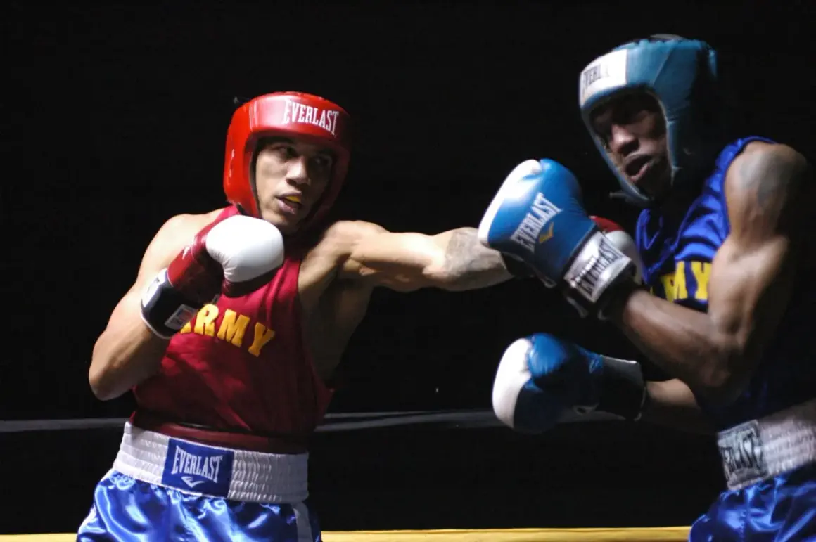 Boxer in red throws a left hook, demonstrating why is the left hook so devastating. His opponent in blue braces for impact.