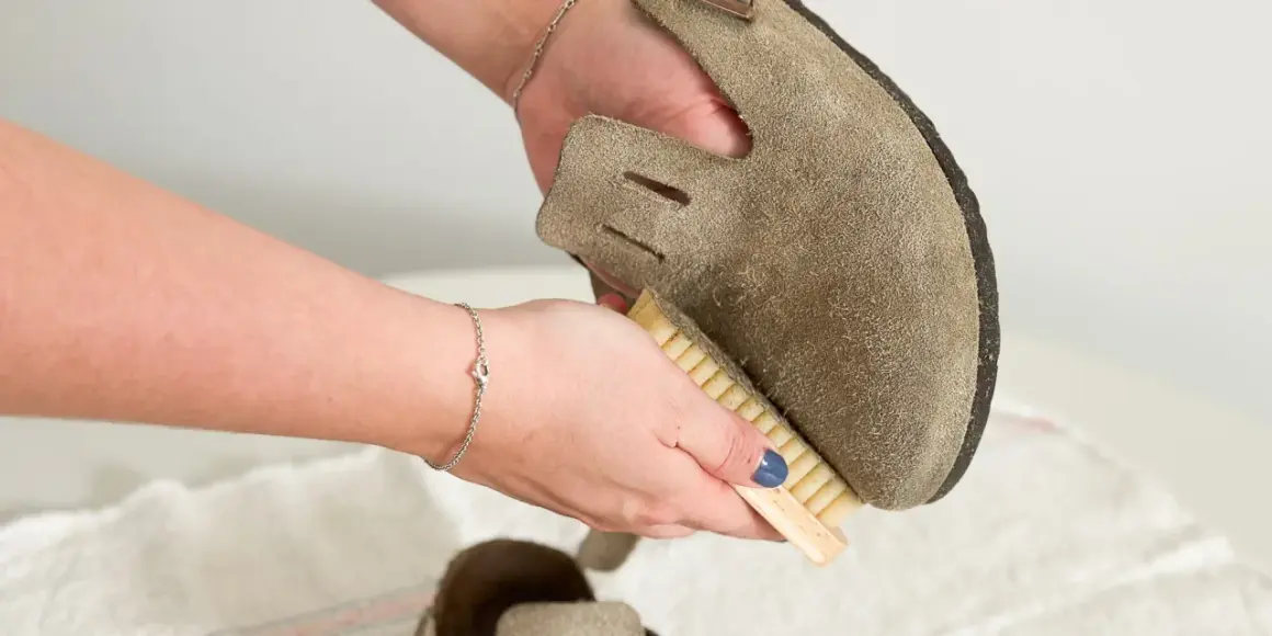 Hände reinigen Wildlederschuh mit Bürste. So lassen sich hartnäckige blutflecken aus leder entfernen und das Material wird wieder wie neu.