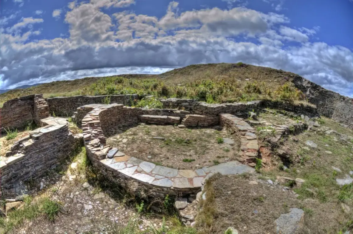 Ruinas circulares de piedra del castro de Formigueiros, con muros bajos y un patio central.