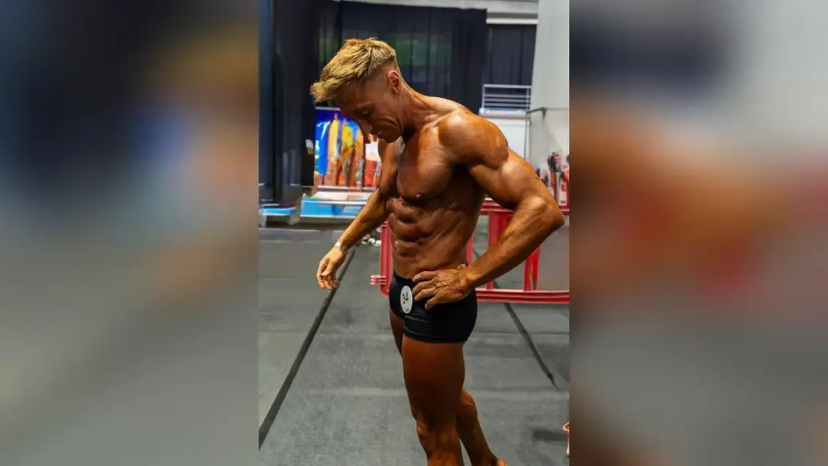 Ein Mann mit beeindruckendem **men's physique** posiert, seine Muskeln sind definiert und gebräunt.
