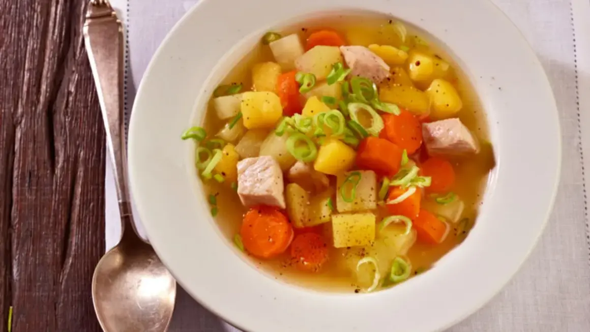 Herzhafter Kohlrabi-Eintopf mit Fleischwürfeln, Kartoffeln und Karotten, garniert mit Frühlingszwiebeln.