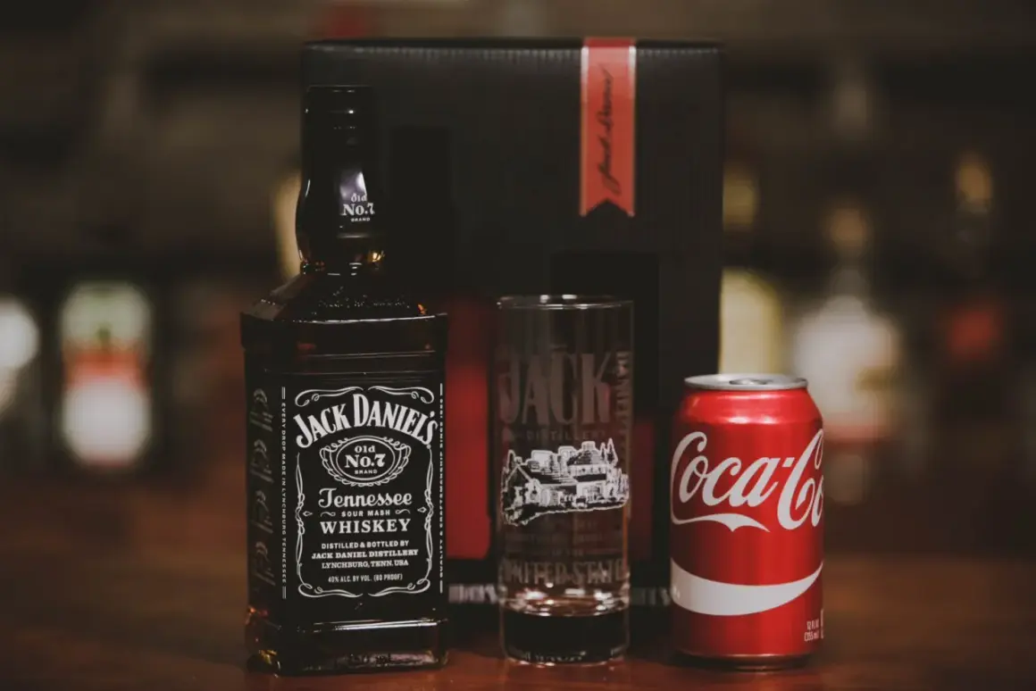 Zestaw na drinka: butelka Jack Daniel's, szklanka z logo destylarni i puszka Coca-Coli. Idealny na wieczór z klasycznym jack and coke.