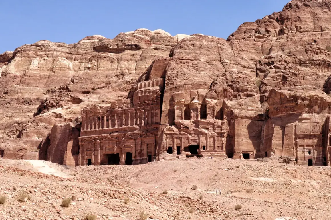 Ancient rock-cut tombs and facades carved into a sandstone cliff face in Petra, Jordan.