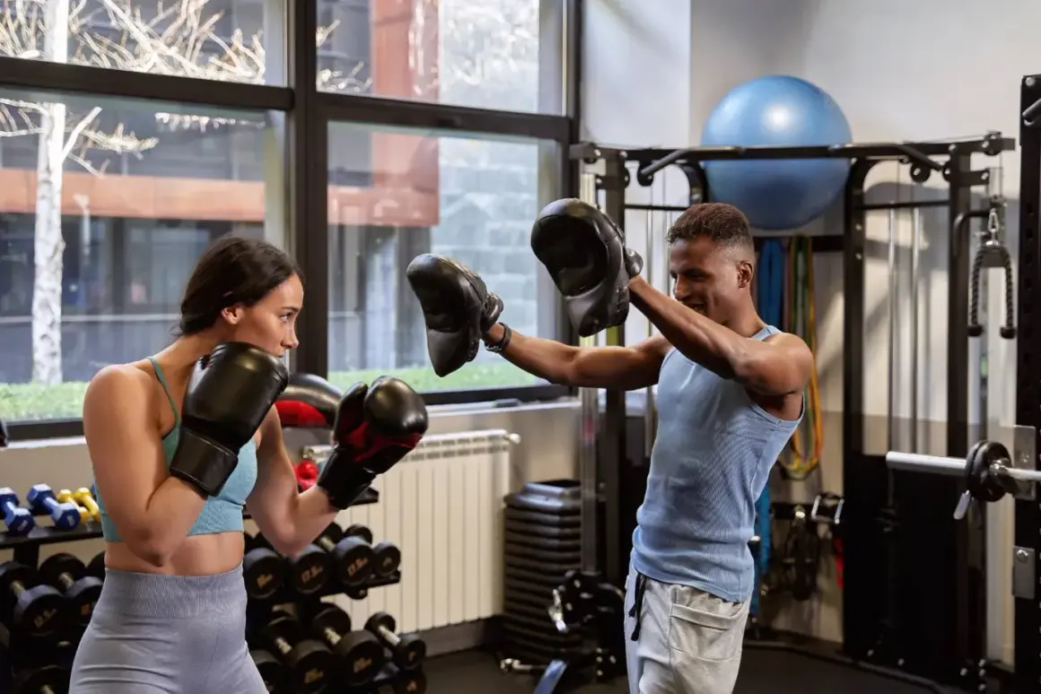 A woman and man in boxing gloves train in a gym. This is how boxers recover after a fight, by staying active and focused.