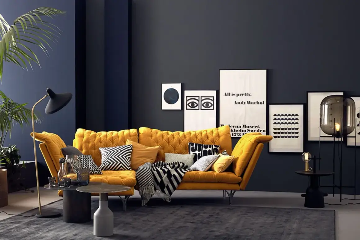 Ein senfgelbes Sofa kombiniert mit grafischen Kissen und einer dunklen Wand schafft einen modernen Look.