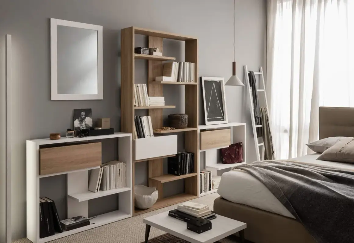 Moderna camera da letto con specchio, letto, e diverse piccole librerie piene di libri e oggetti decorativi.