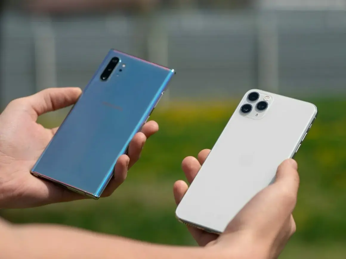 Dwie dłonie trzymają telefony: niebieski Samsung i biały iPhone. Który wybierasz?