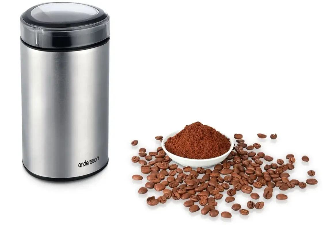 En kaffekvarn i metall bredvid en skål med kaffepulver och bönor. Perfekt för att lära sig hur brygger man kaffe.