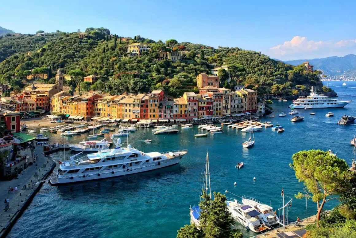 Portofino: cosa vedere? Un incantevole borgo ligure con case colorate, un porto pieno di yacht e una collina verdeggiante.