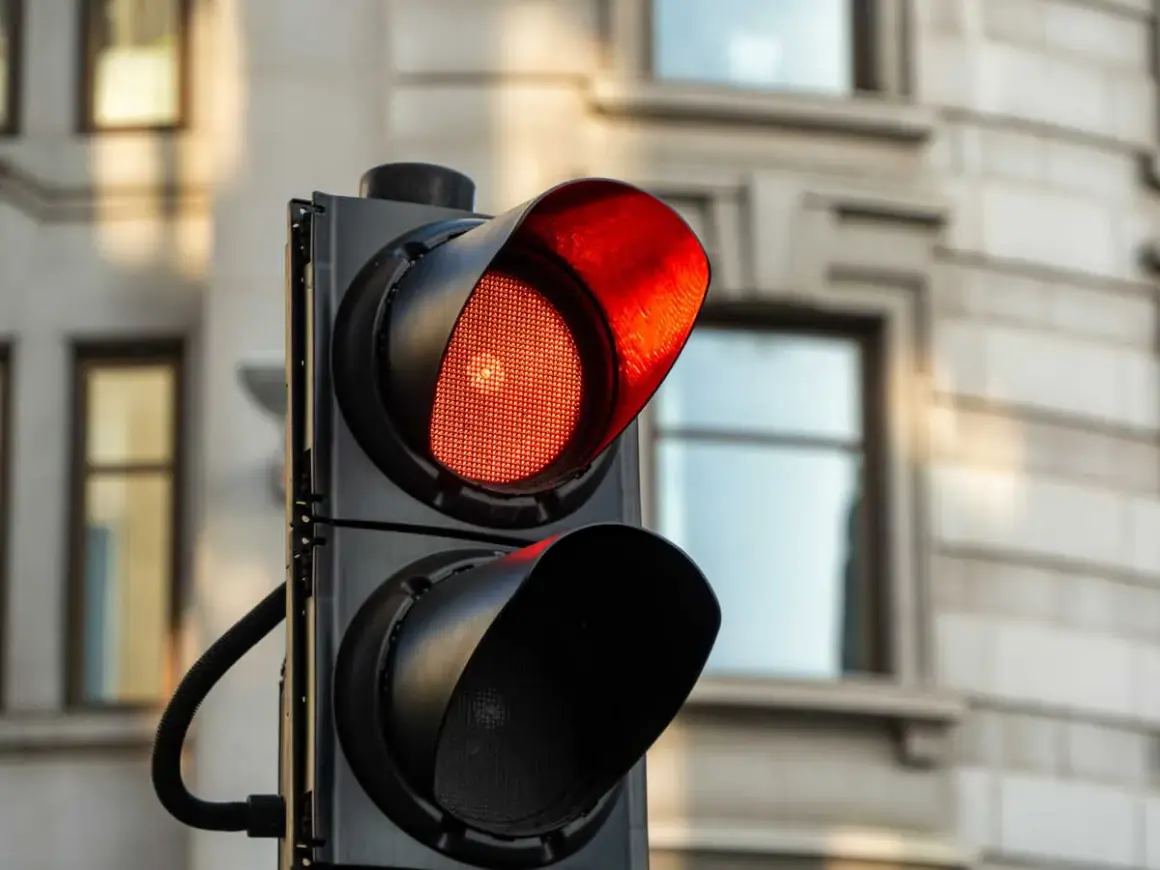 Un feu rouge clignote, signalant un danger. Le radar est prêt à flasher une fois.