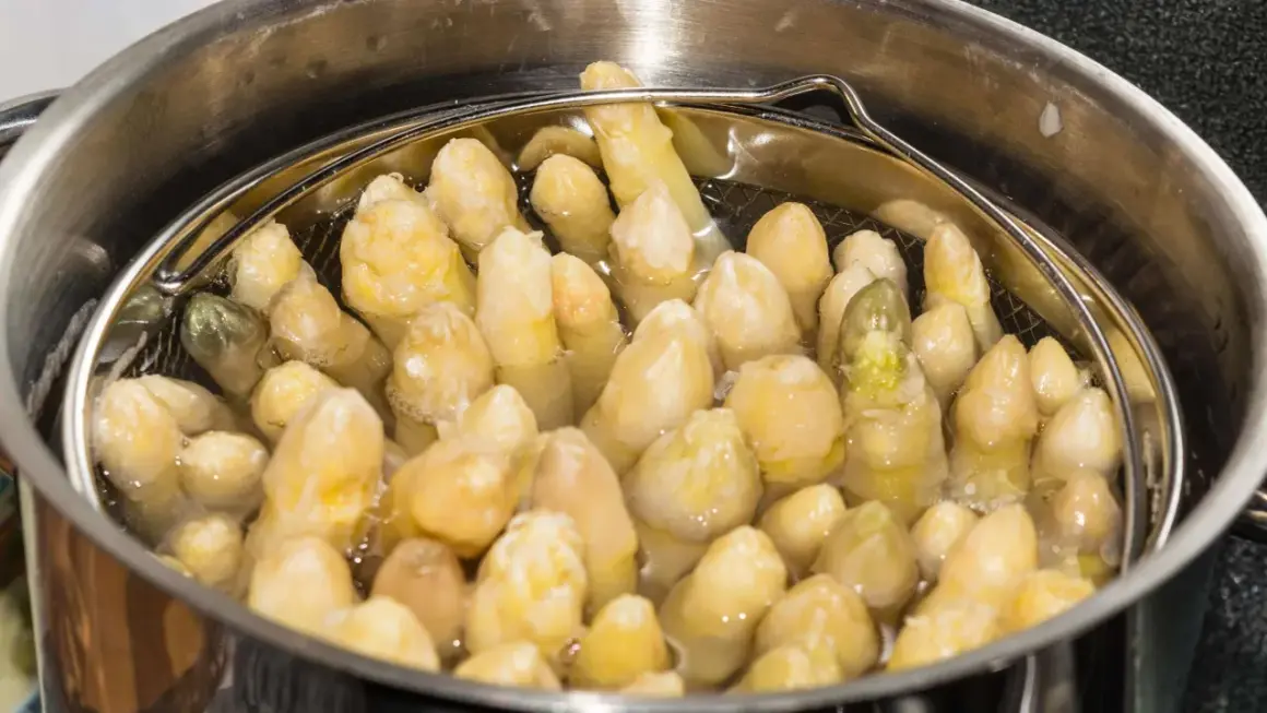 Spargel im Spargeltopf kochen. Die weißen Stangen garen in siedendem Wasser, bereit für ein köstliches Gericht.