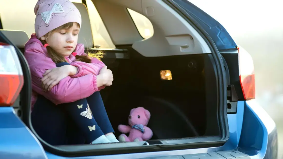 Traurige Kinder im Kofferraum, nur ein Teddybär als Gesellschaft.