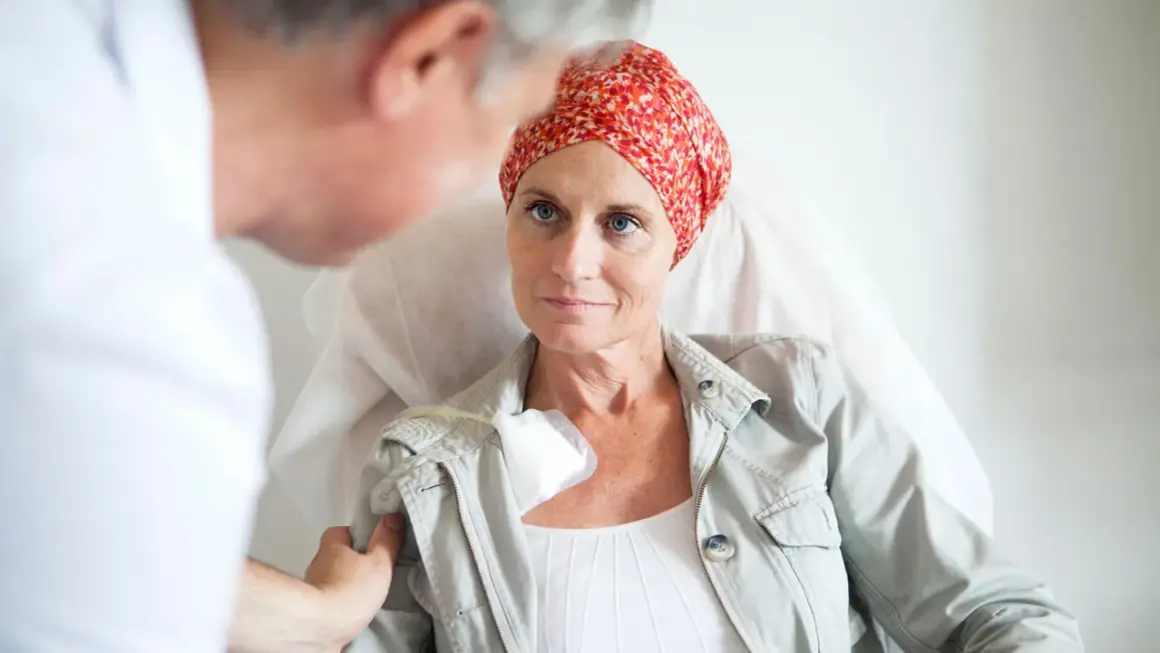 Ärztin spricht mit Patientin, die eine Kopfbedeckung trägt, während sie eine hyperthermie therapie erhält.