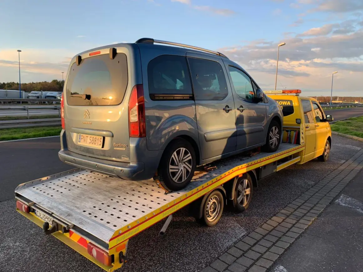 Niebieski Citroen Berlingo na żółtej lawecie. Pomoc drogowa HDI assistance w akcji, holowanie pojazdu po awarii.