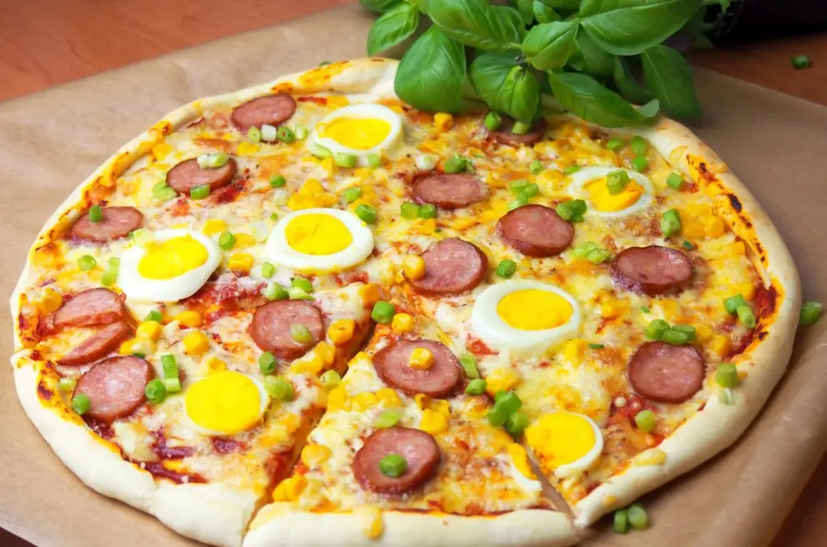 Apetyczna pizza z jajkiem, kiełbasą i kukurydzą, posypana szczypiorkiem. Idealna na szybki obiad.