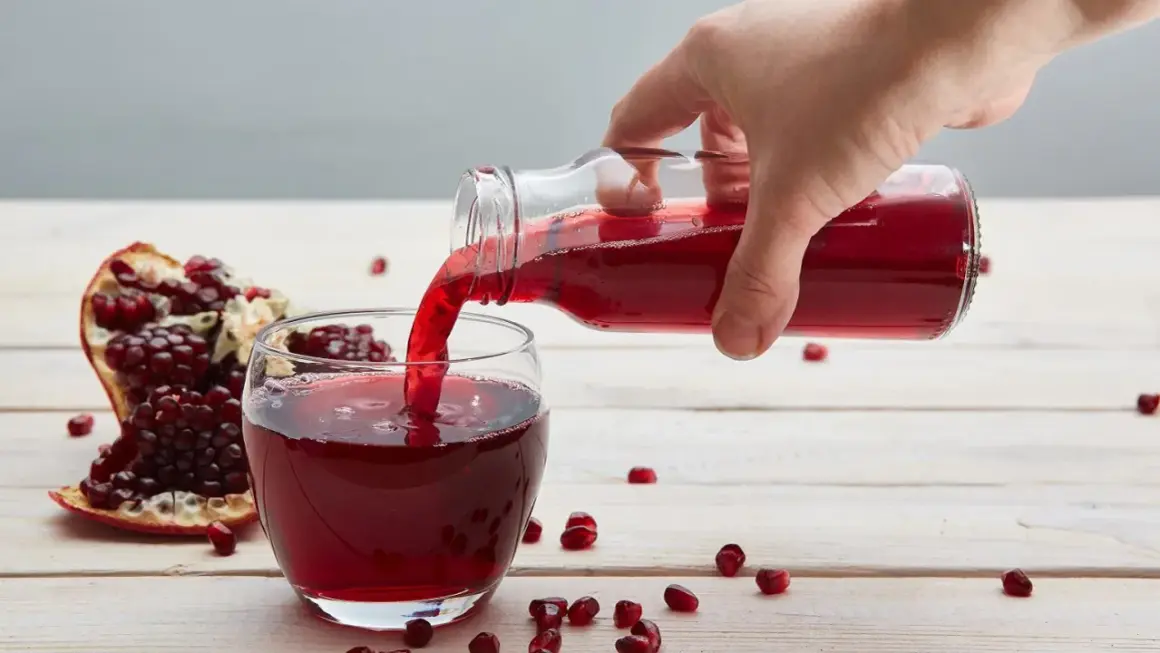 Ręka nalewa sok z granatu do szklanki. Obok leży połówka owocu. Ile pić dziennie?