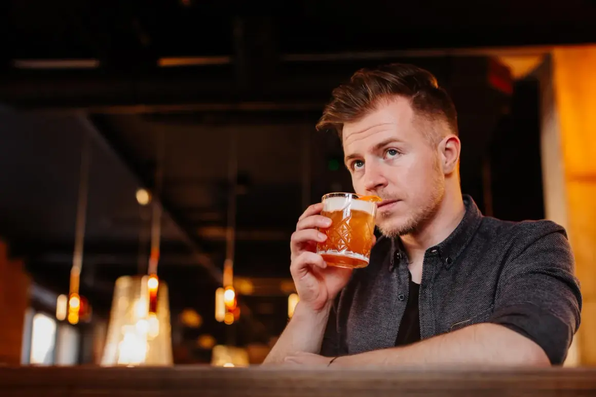Mężczyzna popija drinka, który wygląda jak klasyczny whisky sour. Idealny przepis na wieczór.