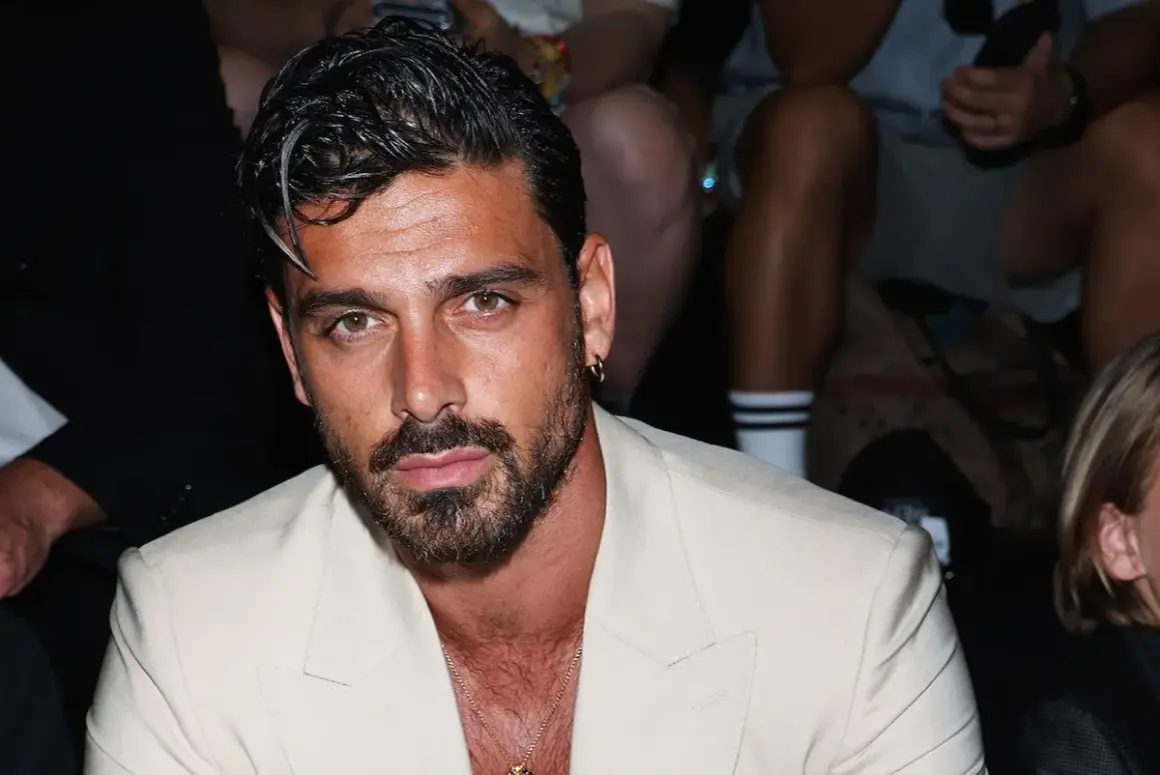 Uomo con capelli sfumati corti, barba curata e un completo chiaro.