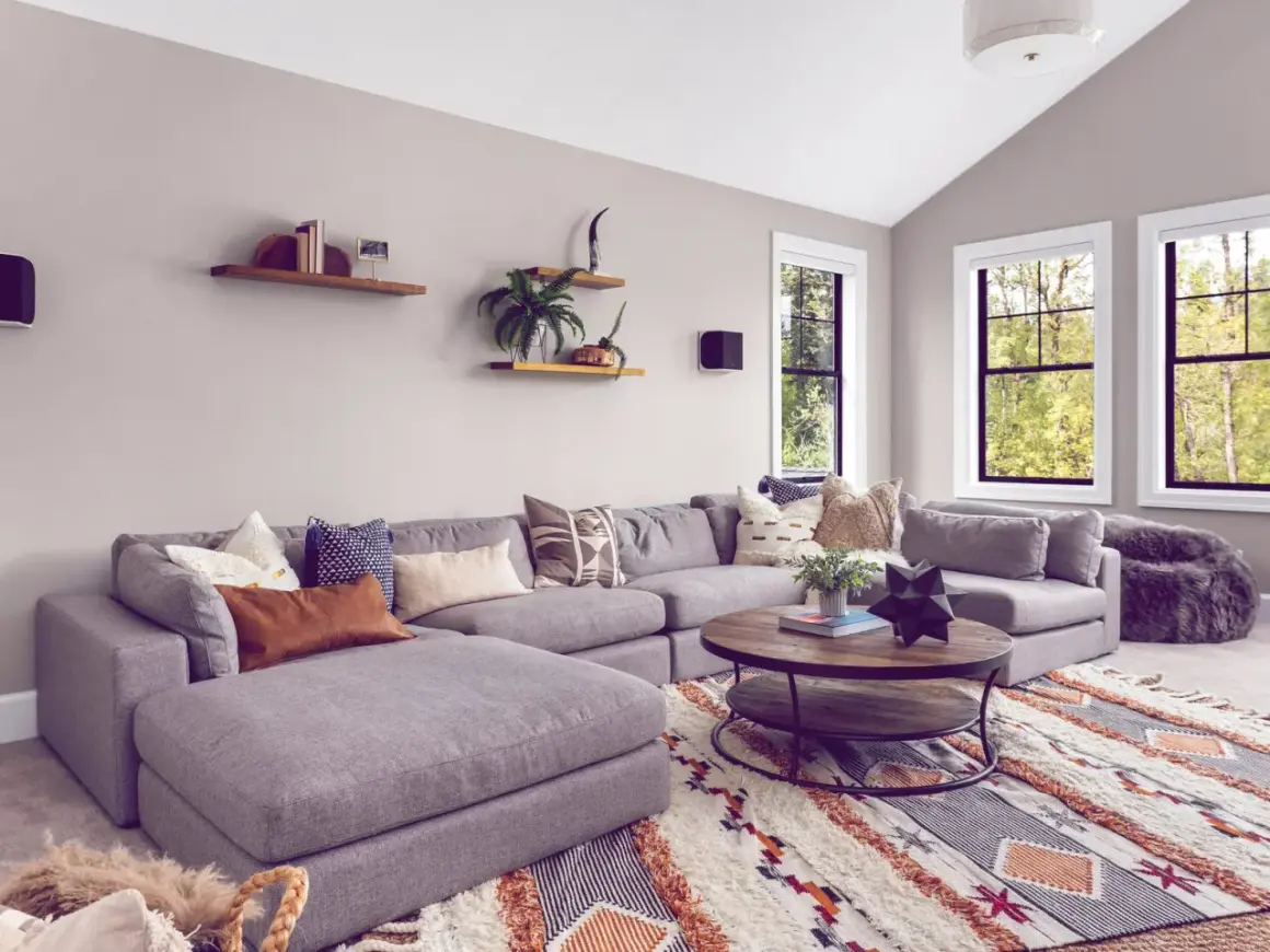 Gemütliches Wohnzimmer mit großem Ecksofa, Kaffeetisch und einem auffälligen Teppich im Boho-Stil, der den aktuellen Teppich Trend widerspiegelt.
