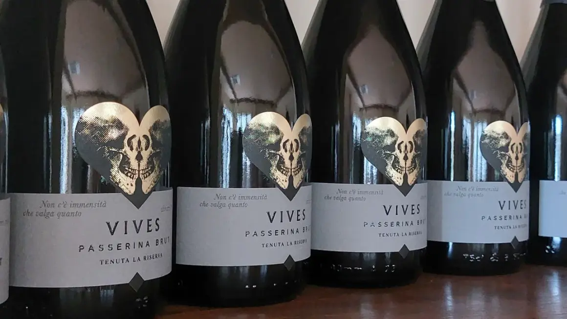 Bottiglie di Vives Passerina Brut, un vino fermo o frizzante, con etichetta a forma di cuore con teschio dorato.