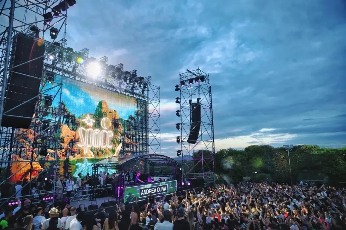 Un grande pubblico balla sotto un cielo nuvoloso, mentre sul palco del **Space Ibiza chiuso** risplende il nome di Andrea Oliva.