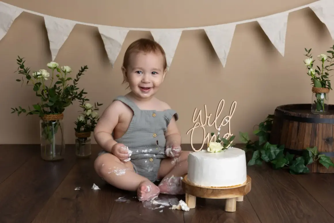 Glad baby firar 1-årsfotografering med tårta. Tips för en lyckad fotografering: lekfull miljö, tårta och glada barn.