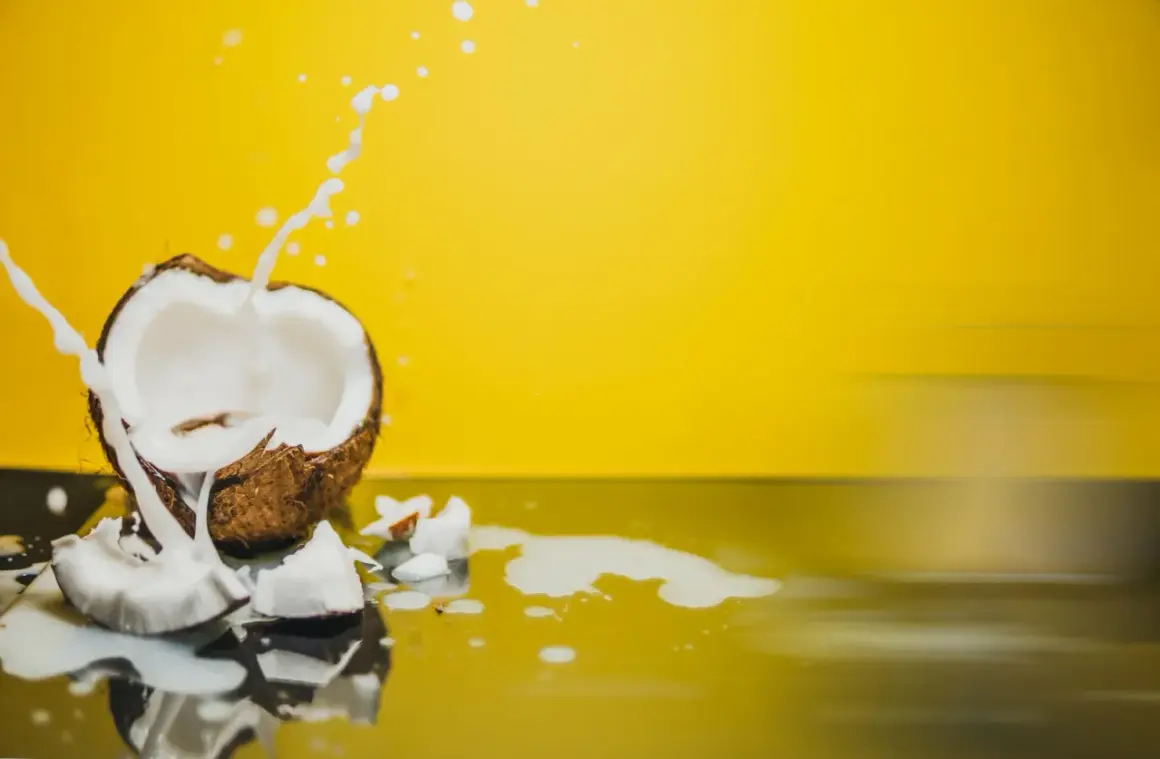 Éclaboussures de lait de coco sur fond jaune vif, révélant la texture crémeuse du lait de coco.