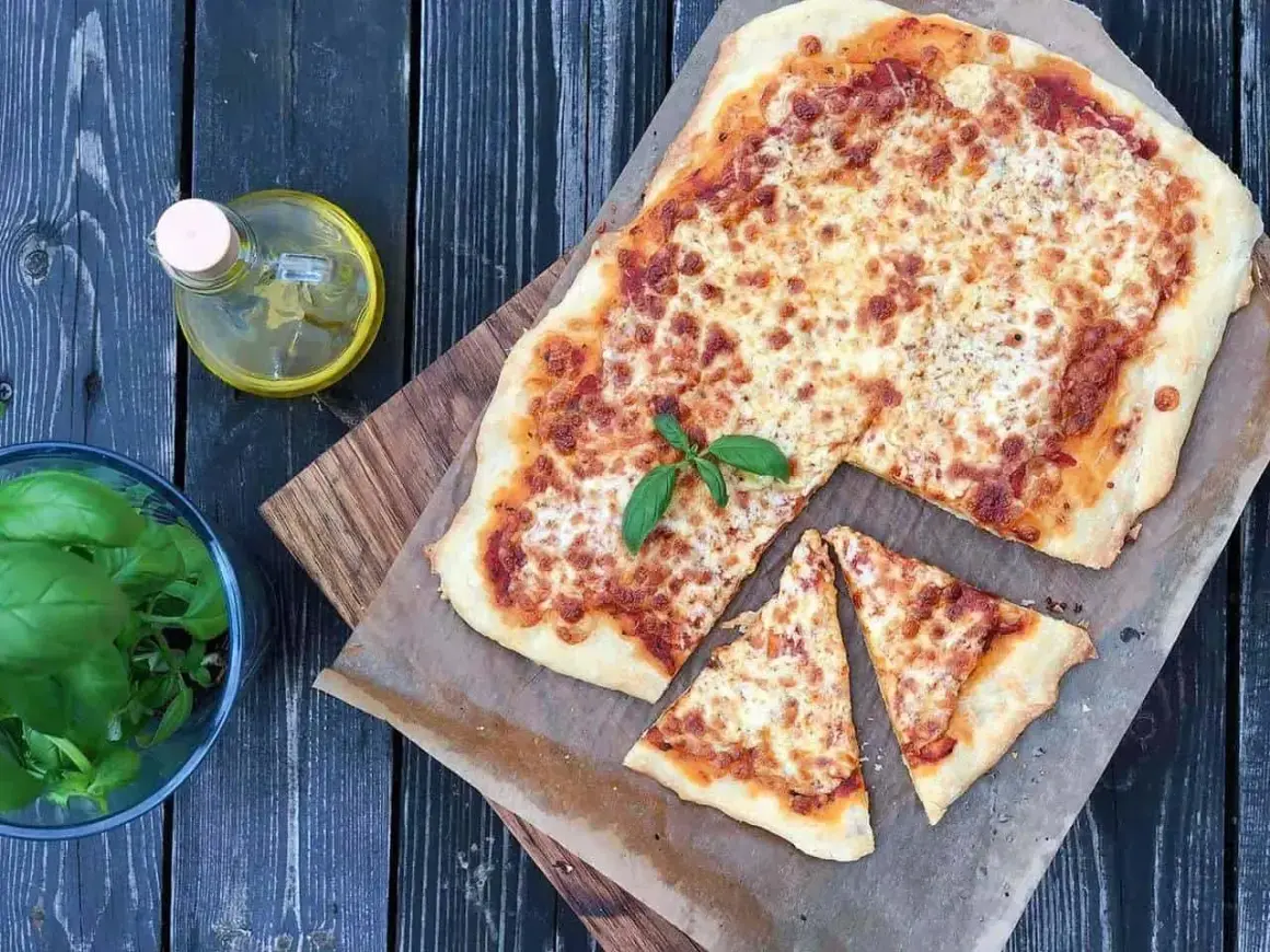 Pyszna pizza margerita z bazylią, oliwą i pomidorami. Idealna na letni wieczór.