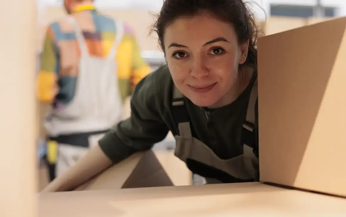 Donna sorridente con scatole, pronta per organizzare un trasloco senza stress.