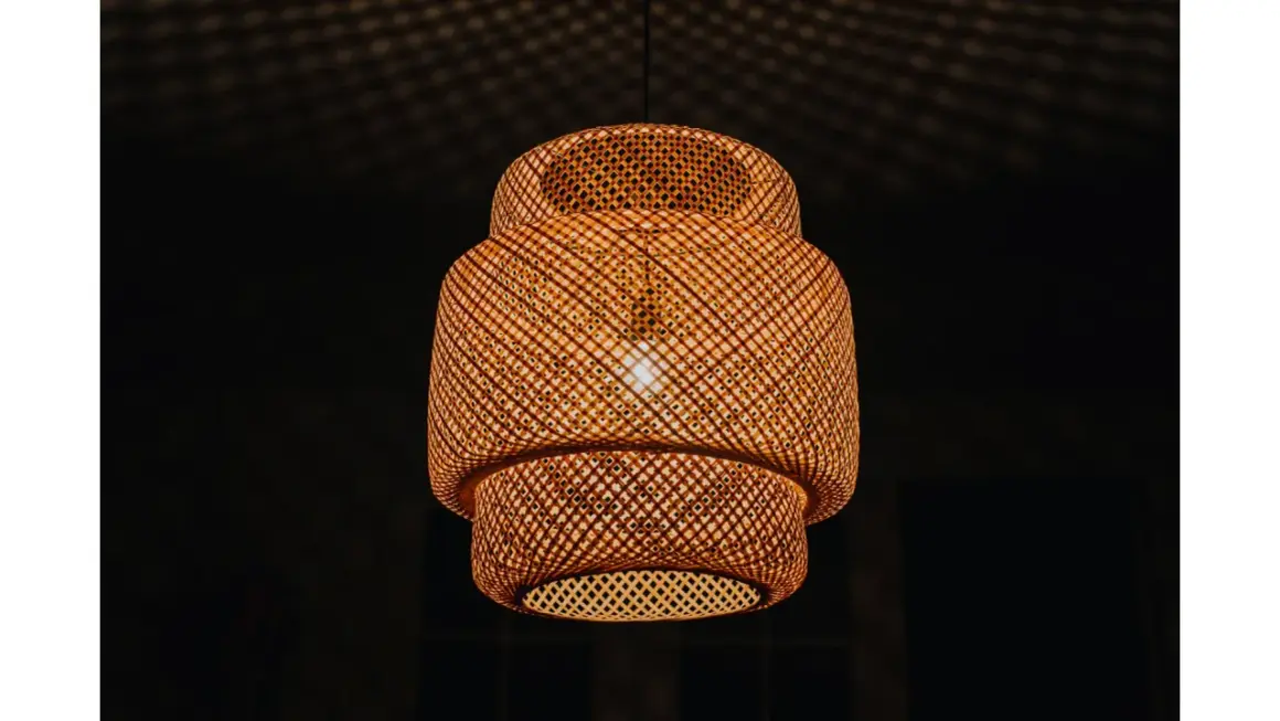 Pleciona, bambusowa lampa ruchoma rzuca na sufit cień przypominający siatkę.