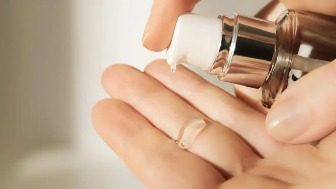Eine Hand empfängt einen Tropfen einer klaren, gelartigen Creme mit Hyaluronsäure aus einem Spender.