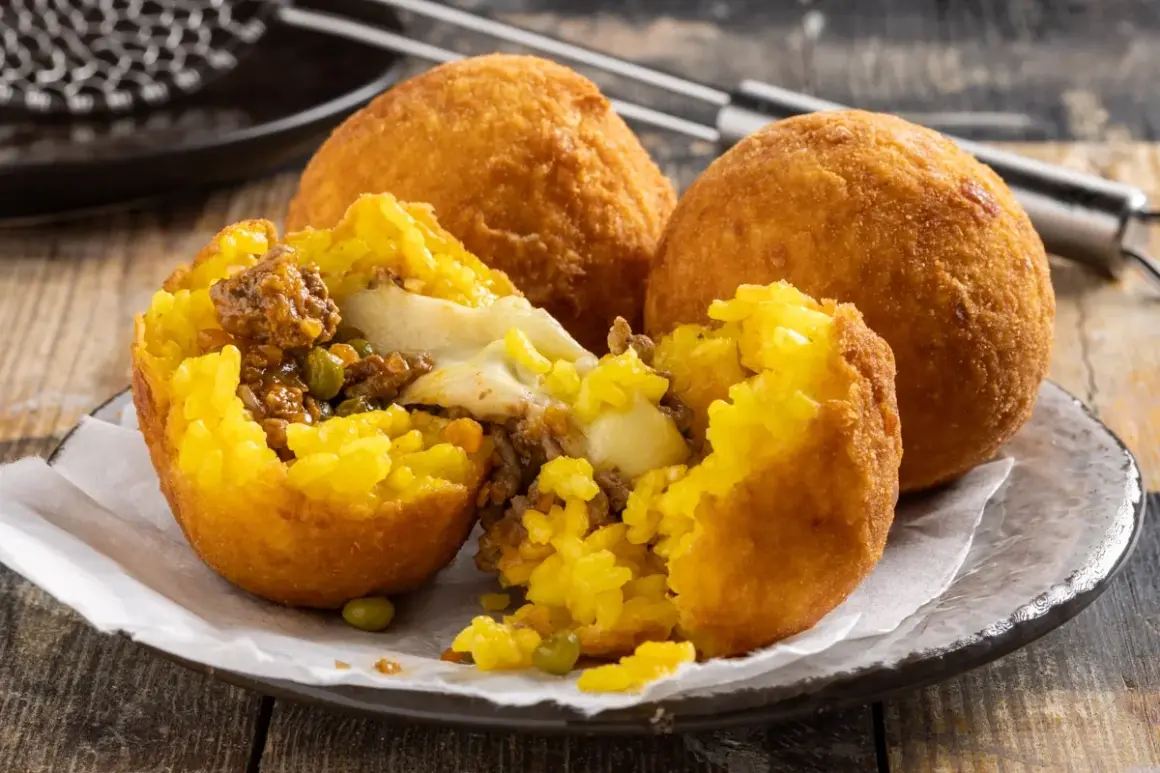 Arancini ripieni di carne e formaggio filante, un esempio di come si fanno gli arancini siciliani, dorati e croccanti.