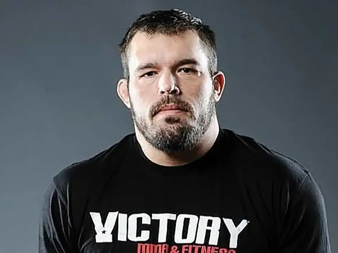 Dean Lister, en tuff MMA-fighter med skägg och en svart t-shirt med texten "Victory MMA & Fitness".