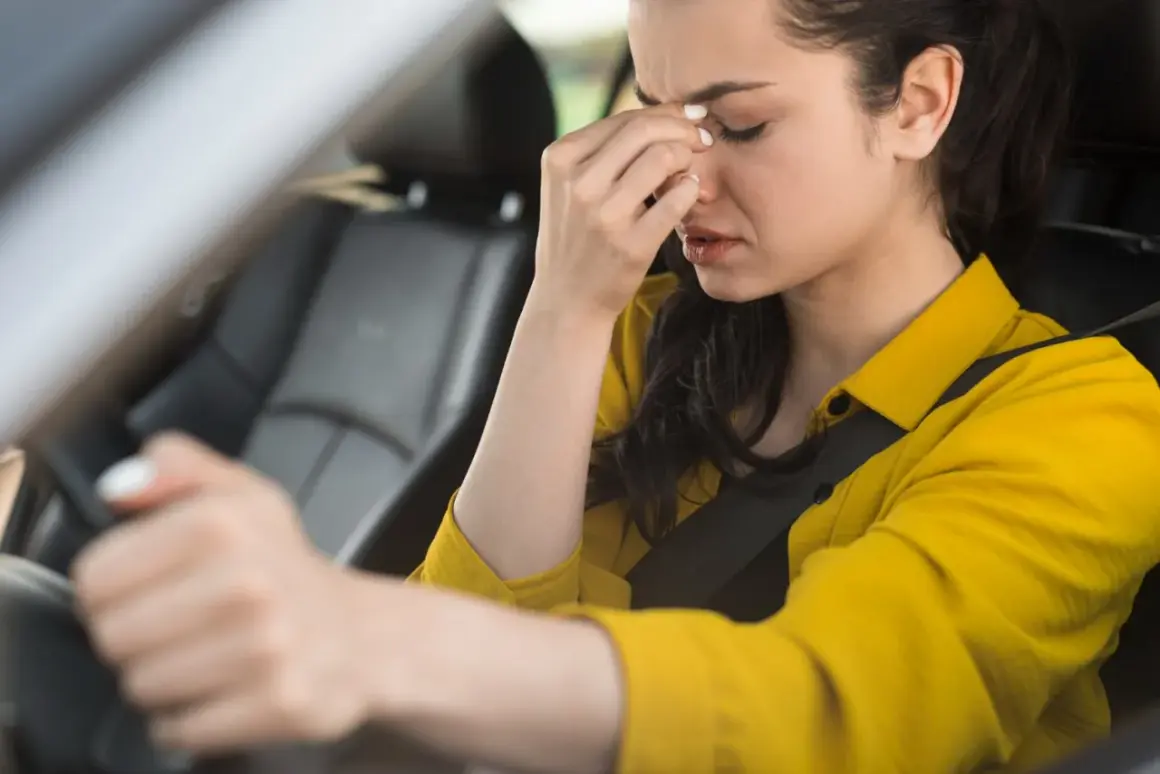 Kobieta w żółtej koszuli siedzi za kierownicą, trzymając się za czoło. Czuje frustrację, bo wciskam gaz, a auto nie przyspiesza.