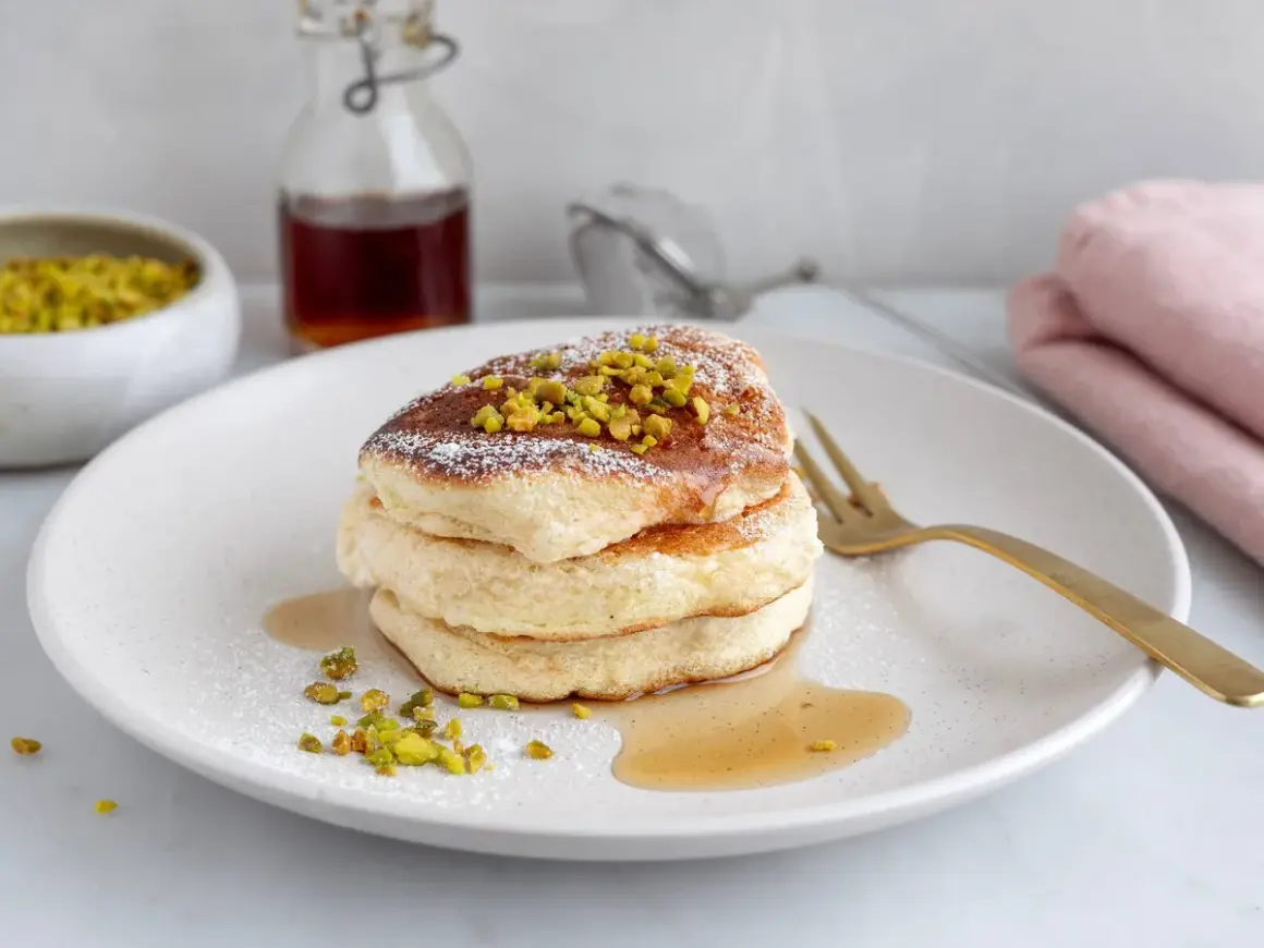 Fluffiga japanska pannkakor toppade med pistagenötter och pudersocker, serverade med sirap.