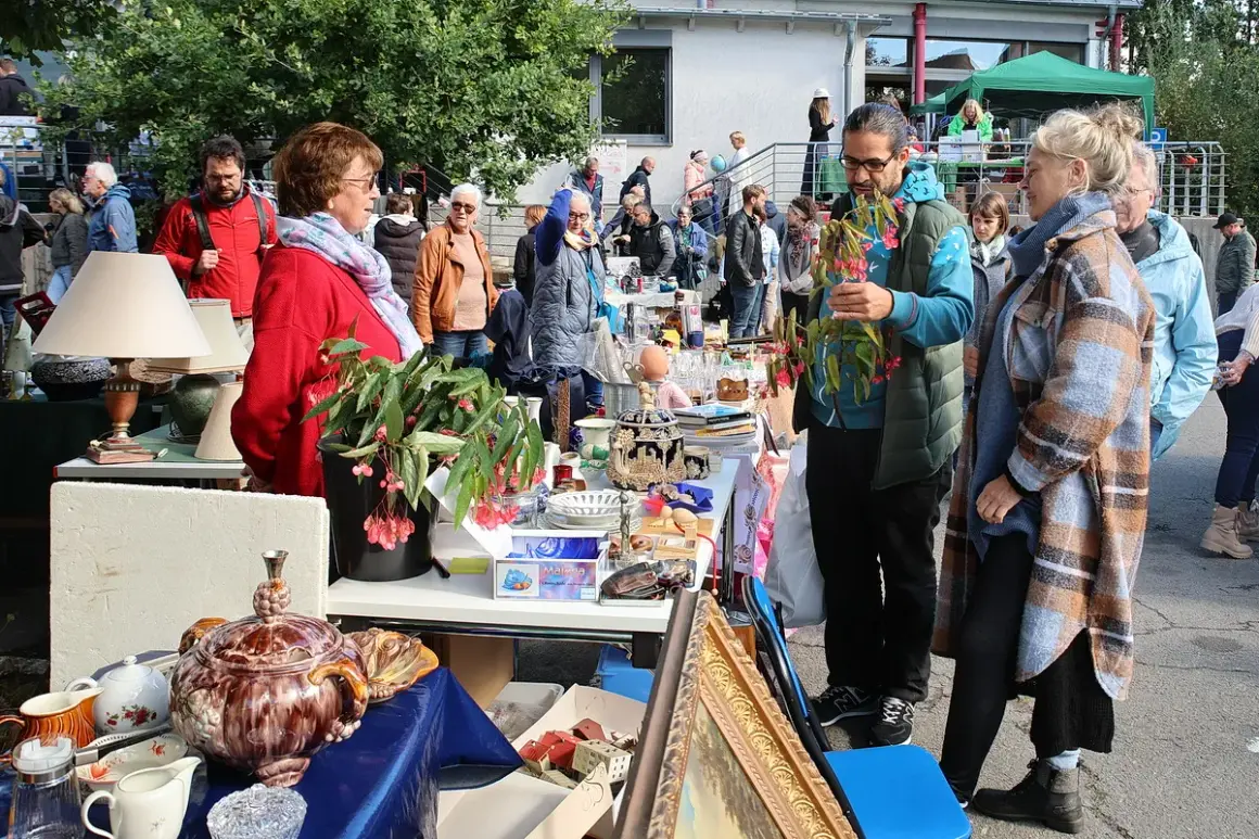 Buntes Treiben auf dem Flohmarkt Overath. Menschen stöbern an Ständen mit Antiquitäten, Lampen und Geschirr.