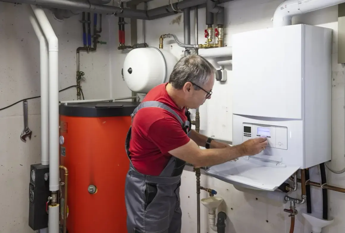 Ein Mann in Latzhose führt eine Emissionsmessung an einer Heizungsanlage durch. Der Schornsteinfeger prüft die Werte am Display.