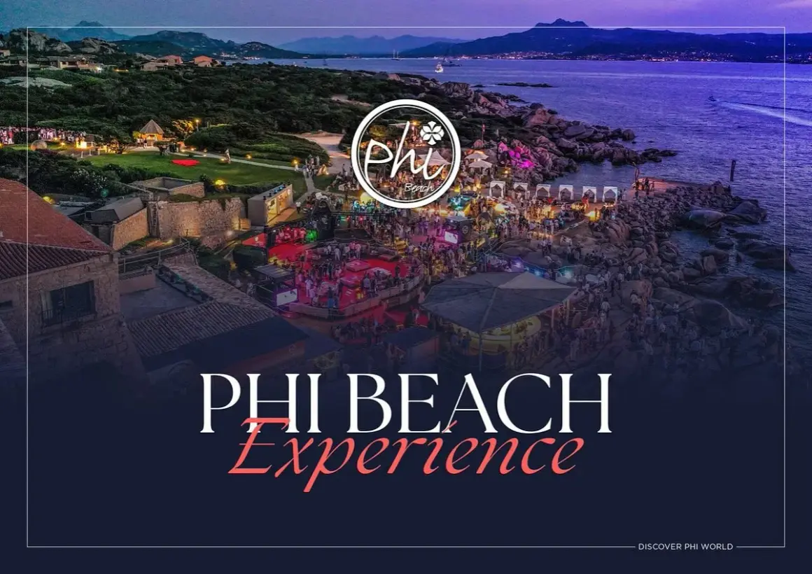 Un'affollata festa al Phi Beach, con luci, musica e gente che balla sulla costa rocciosa al tramonto.