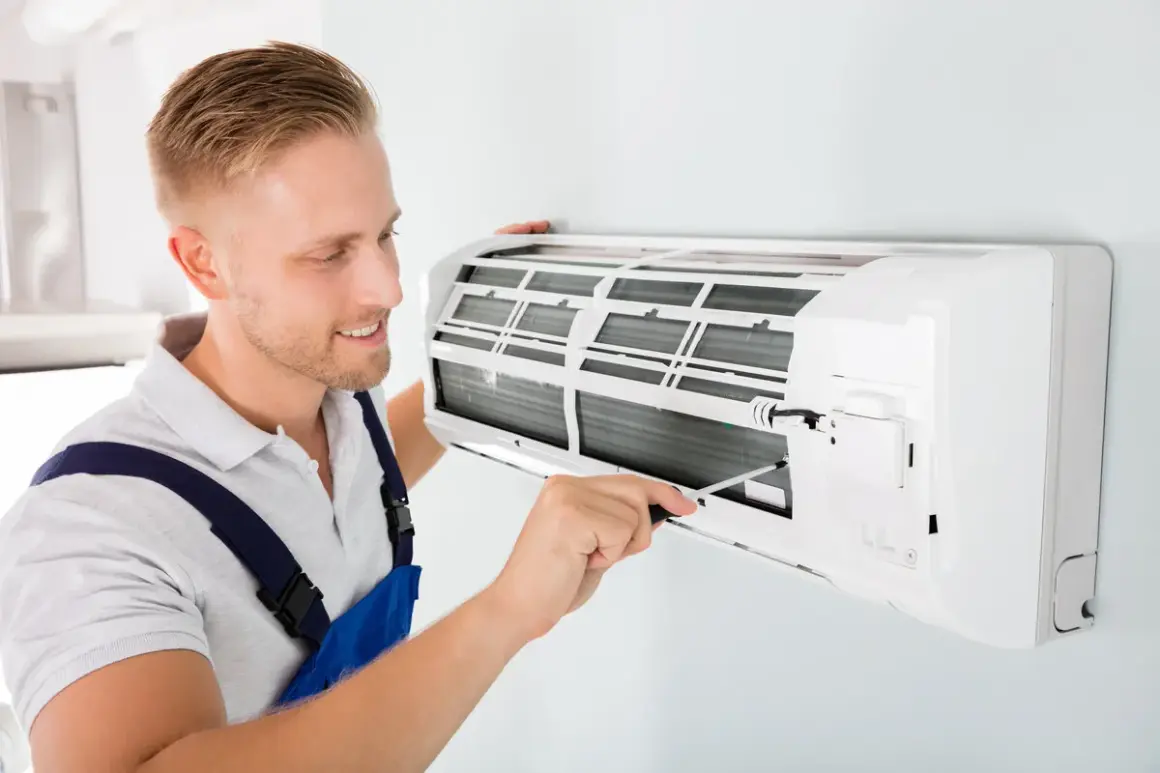 Un technicien ajuste un climatiseur mural. Il s'assure que l'appareil fonctionne bien pour éviter toute mauvaise odeur de climatisation.