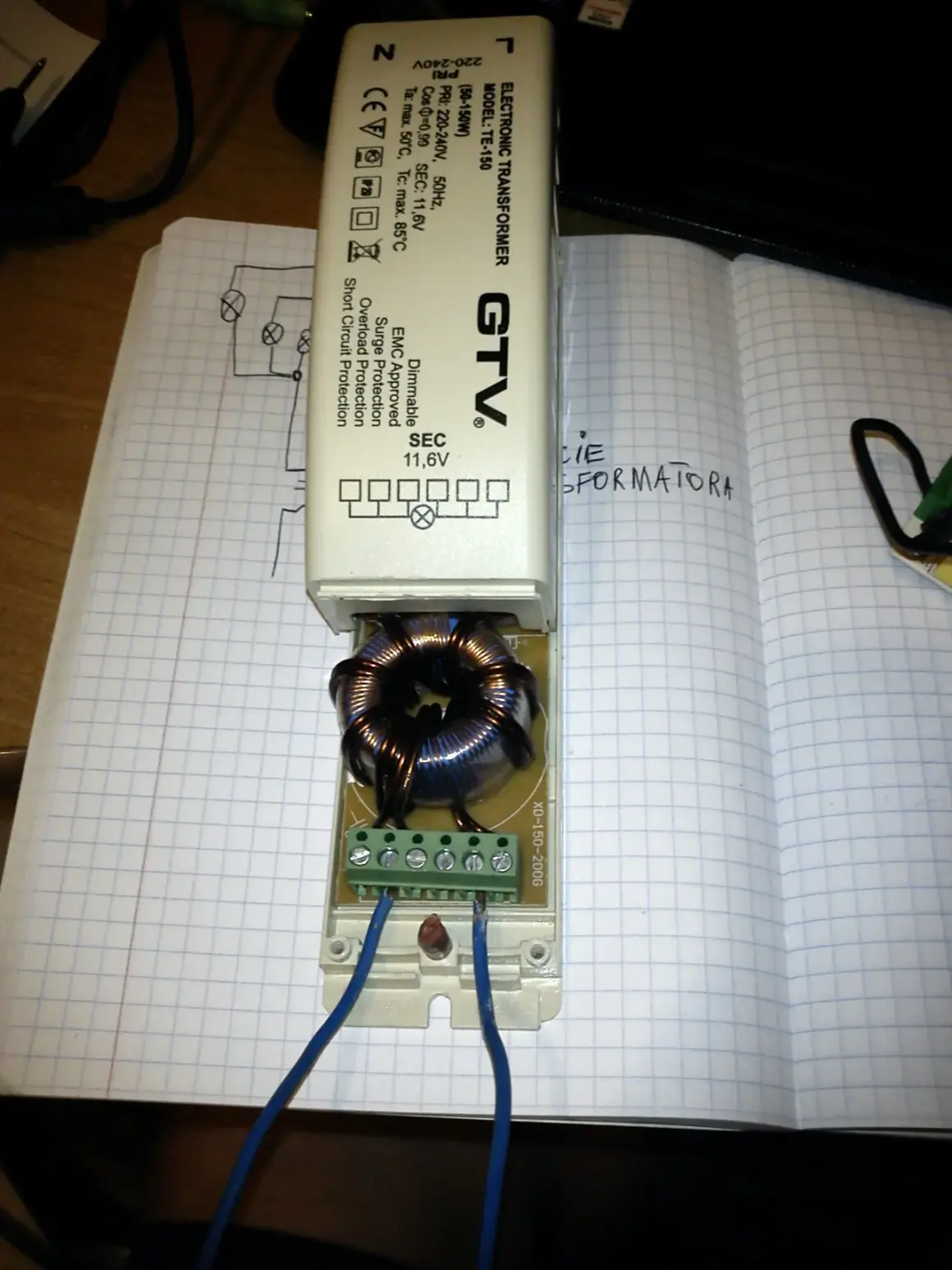 Schemat podłączenia transformatora elektronicznego GTV TE-150. Widać uzwojenie i zaciski do podłączenia przewodów.