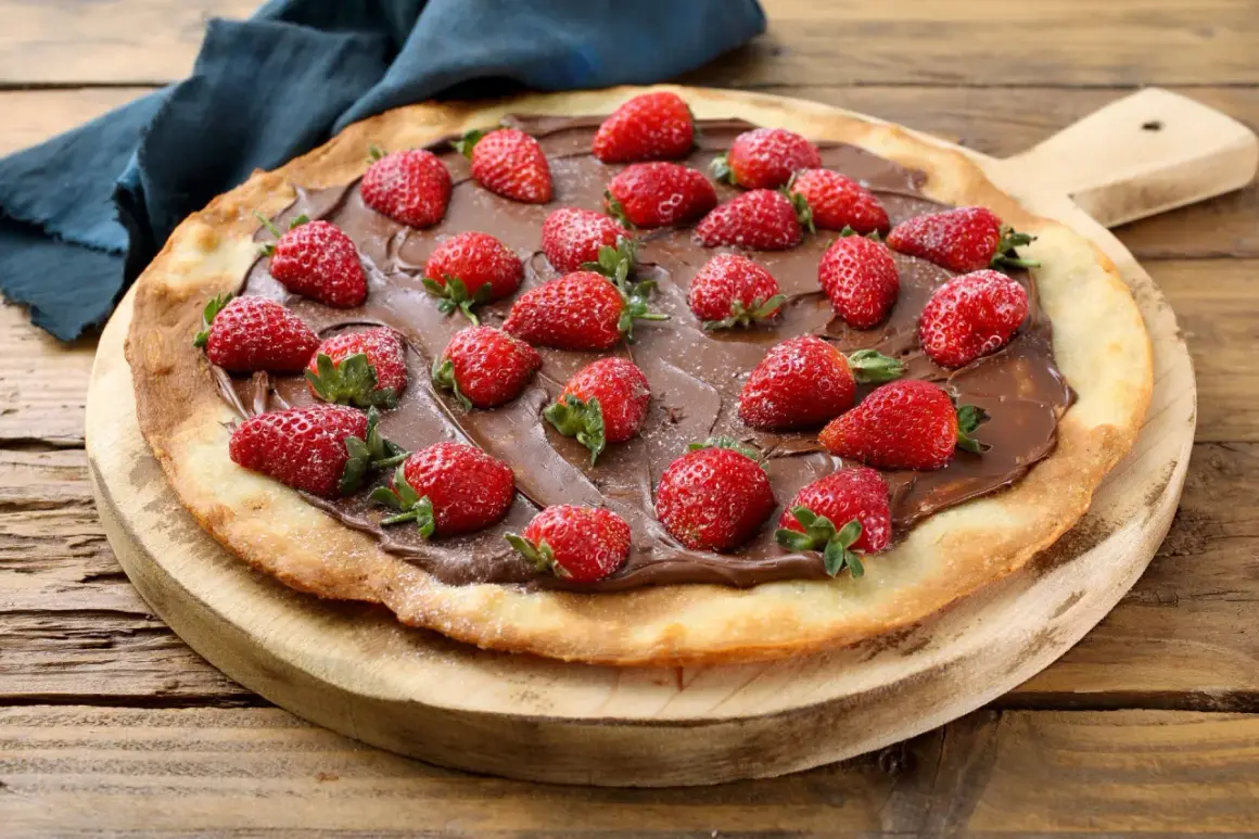 Słodka pizza z truskawkami i kremem czekoladowym na drewnianej desce. Idealna na deser!